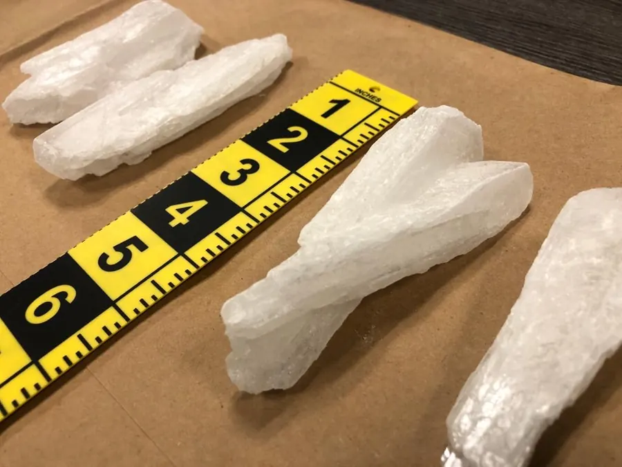 Large crystals of methamphetamine laid next to a yellow evidence ruler